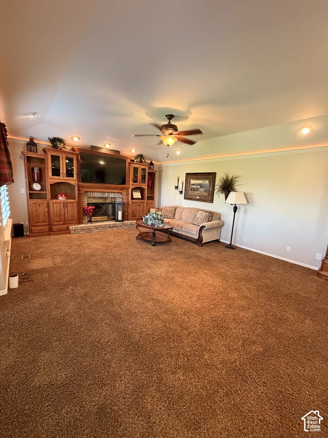 Spacious living area featuring a built-in entertainment center, brick fireplace, ceiling fan, and recessed lighting