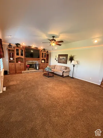 Spacious living area featuring a built-in entertainment center, brick fireplace, ceiling fan, and recessed lighting