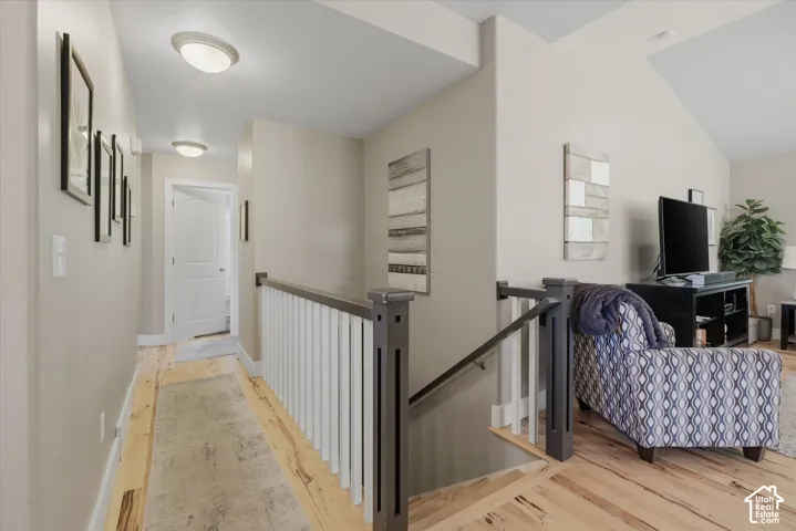 Light wood flooring, white trim, and a staircase with white spindles and dark wood newel posts