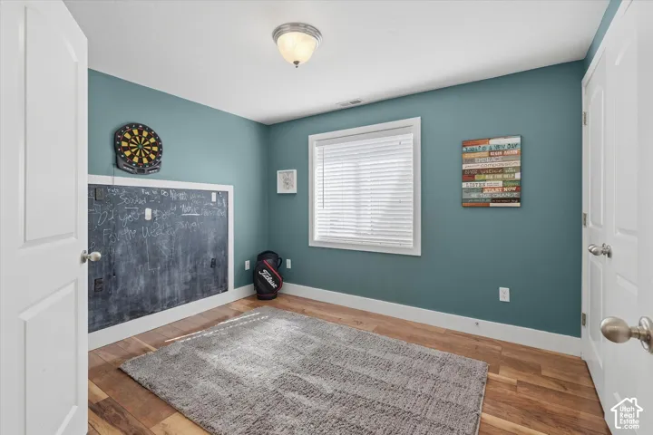 Wood-finish flooring, white trim, and a built-in chalkboard wall