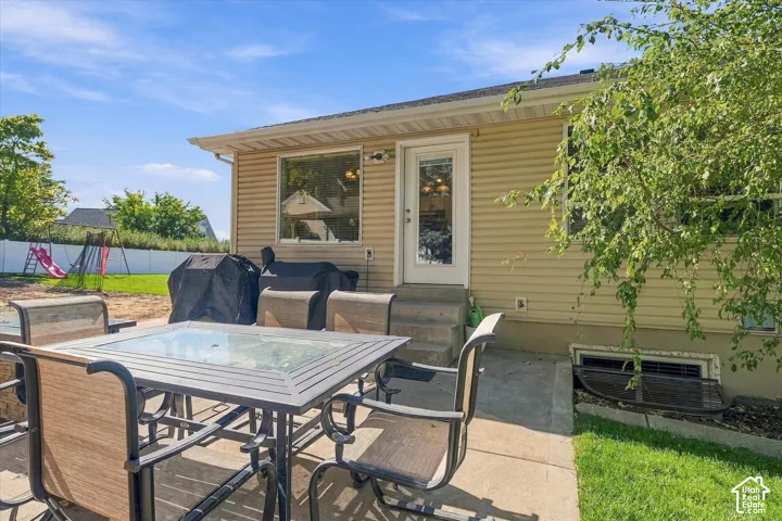 Patio area with concrete hardscaping, light-colored siding, and a white framed door