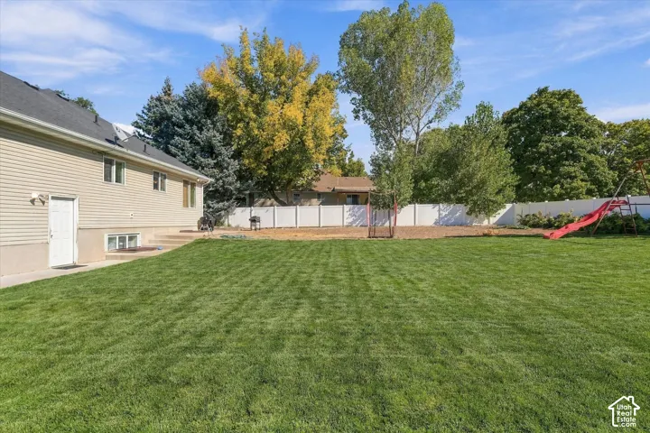 Expansive green lawn, mature trees, and a white privacy fence
