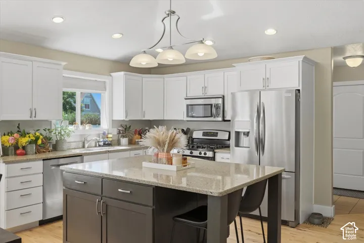 Kitchen featuring white shaker-style cabinetry, a granite-finish island, and recessed lighting