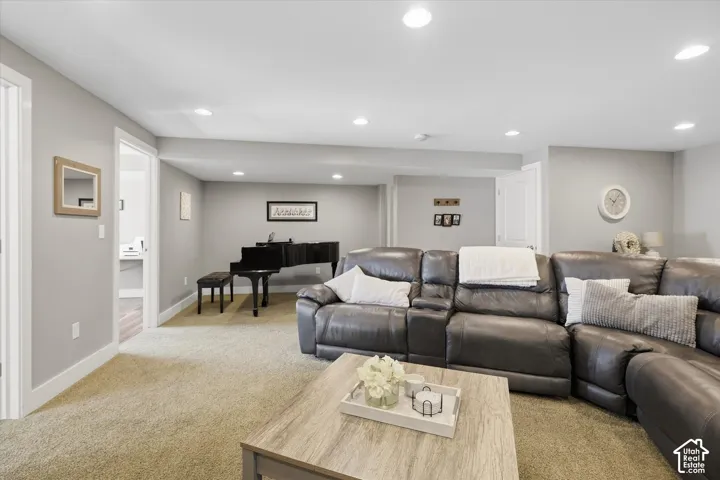 Recessed lighting illuminates the carpeted living area with light gray walls and white trim