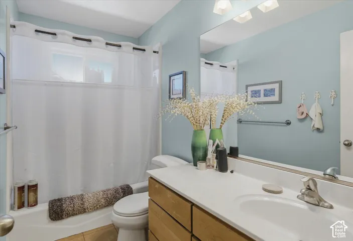 Bathroom featuring a wood-finish vanity with a single basin sink, an integrated mirror, and a full bathtub with a shower