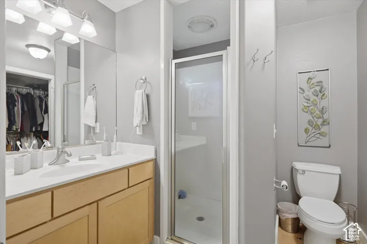 Bathroom featuring a light wood-finish vanity with a white countertop, a mirror, and an enclosed shower