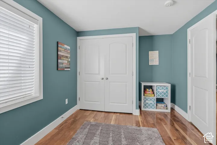 Hardwood flooring throughout, white trim, and a white interior door with an arched panel