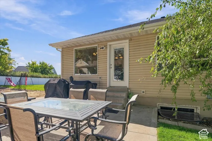 Rear exterior featuring horizontal siding, a glass-paneled entry door, a window with blinds, and a concrete patio