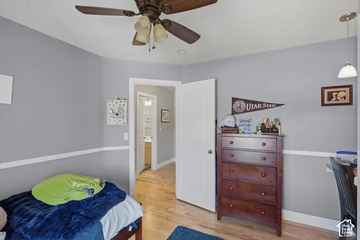 Light wood-finish flooring, ceiling fan, white trim, and a white door frame