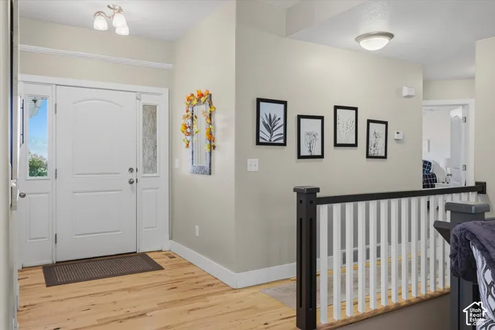 Entryway featuring a paneled door with sidelights, wood-finish flooring, and a two-tone staircase with a dark wood newel post and white balusters
