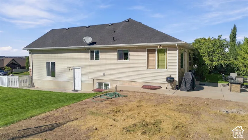 Siding exterior with multiple windows, a rear entry door, and a partially covered patio