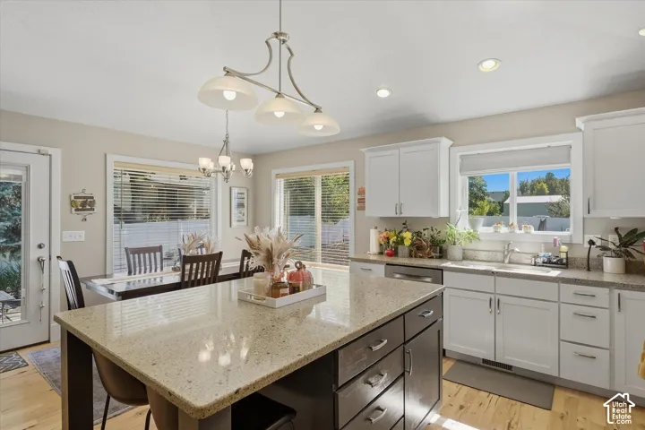 Kitchen featuring a center island with countertop, recessed lighting, wood-finish flooring, white cabinetry, and stainless steel appliances
