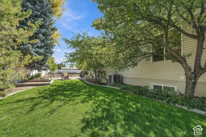 Manicured lawn with mature trees and a private patio area