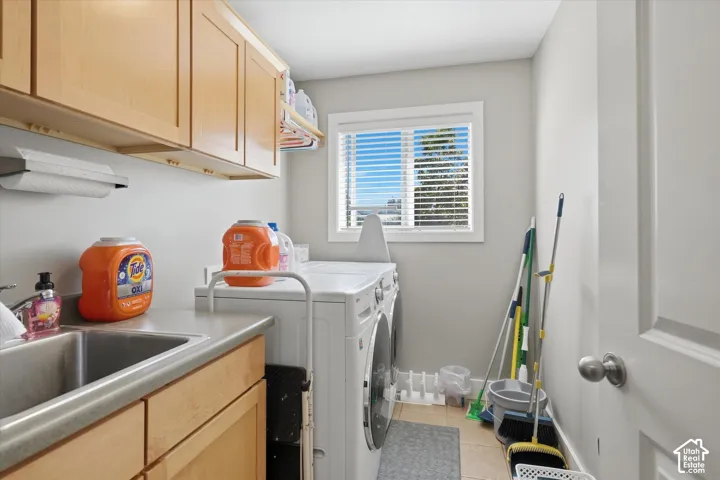 Dedicated utility space featuring built-in cabinetry, a stainless steel sink, and a window with blinds