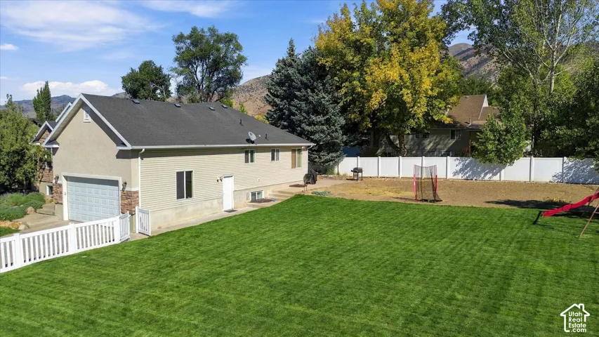 Expansive green lawn with a white picket fence, a privacy fence, and mountain scenery