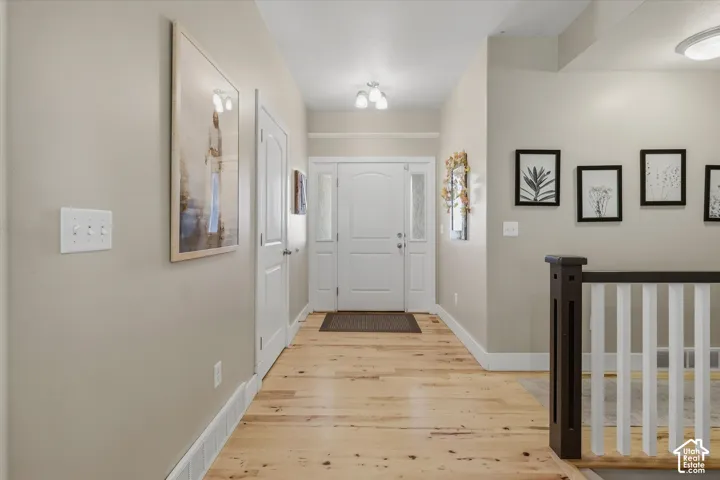 Entryway featuring light wood-finish flooring, a white paneled entry door with sidelights, and recessed ceiling lighting