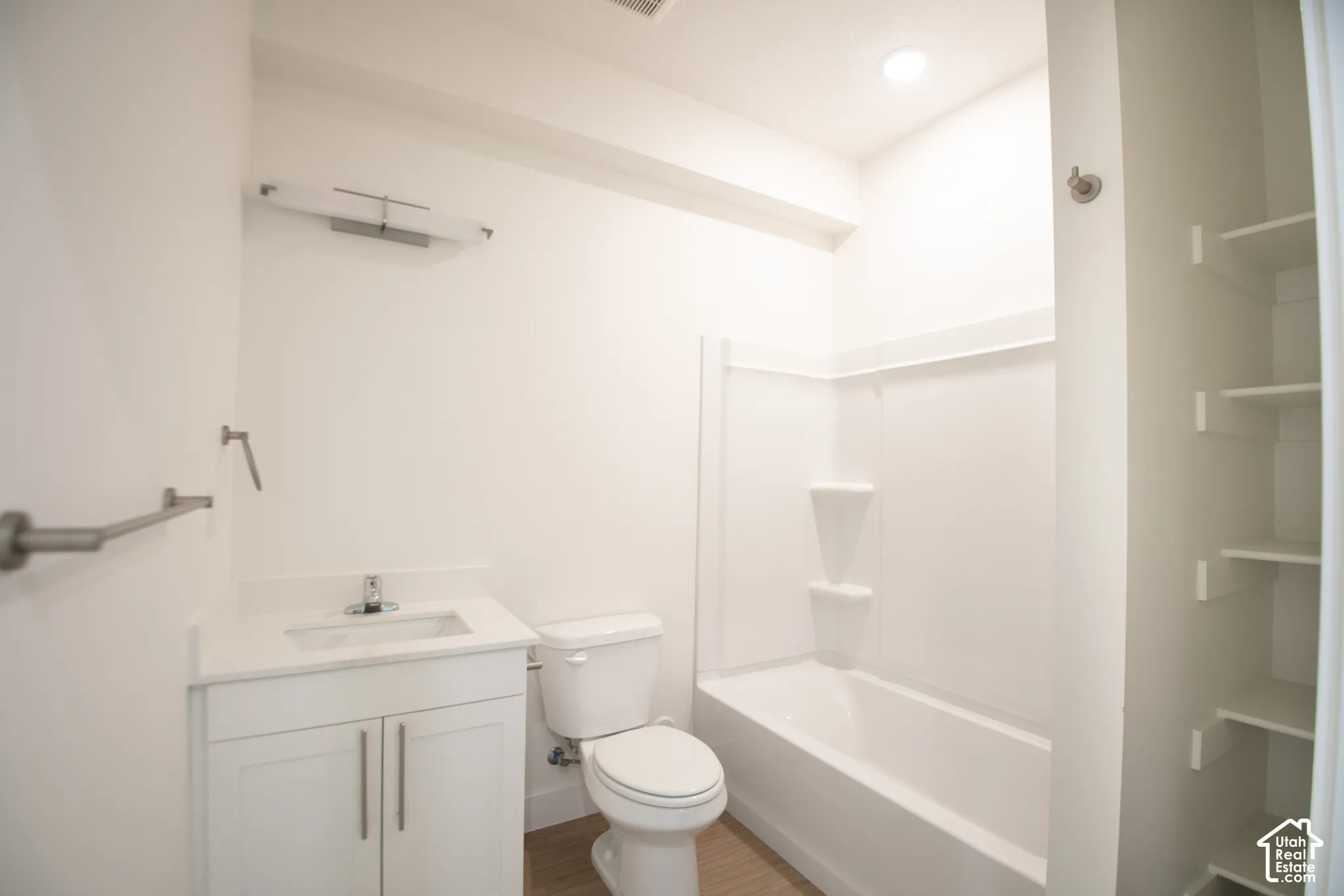 White vanity with shaker-style cabinetry, a white countertop, and a single basin sink