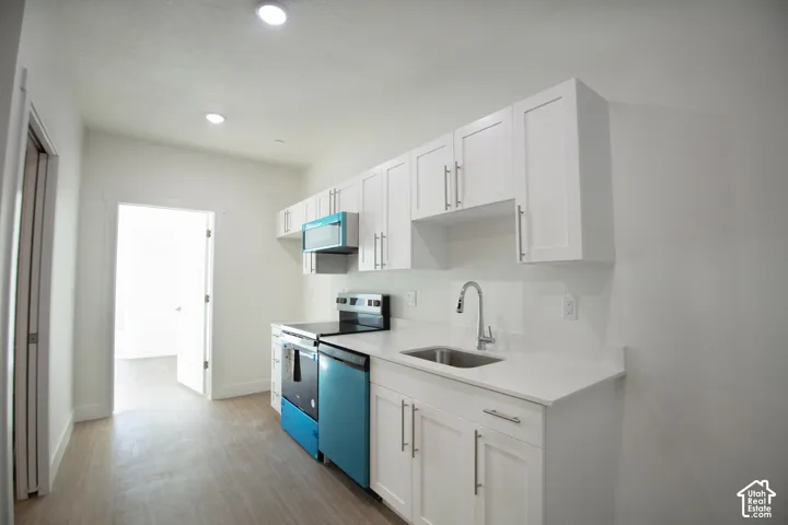 Contemporary kitchen featuring white cabinetry, light-toned countertops, a stainless steel sink with a gooseneck faucet, and recessed lighting