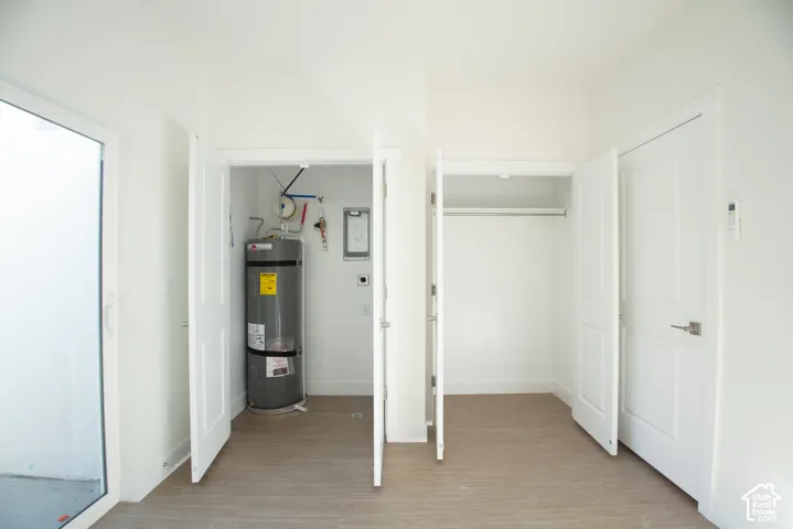 Interior utility space featuring a water heater, white panel doors, and wood-finish flooring
