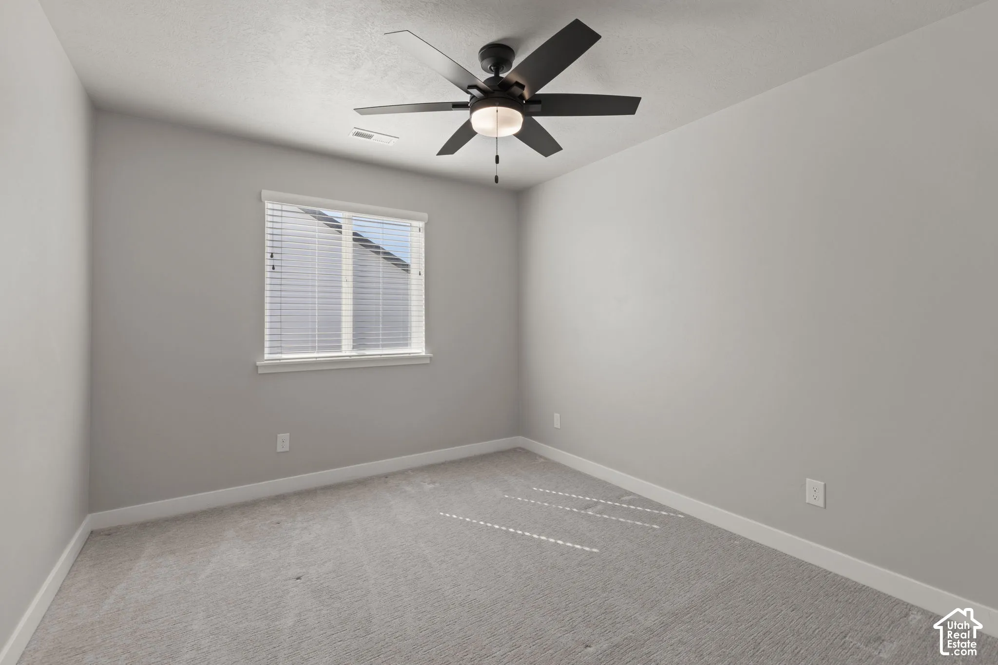 Neutral-toned carpeting, white window trim, and a ceiling fan with integrated lighting