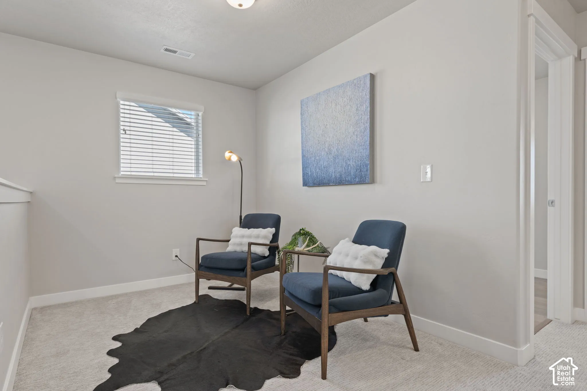 Neutral wall tones, carpeted flooring, and a single window with blinds