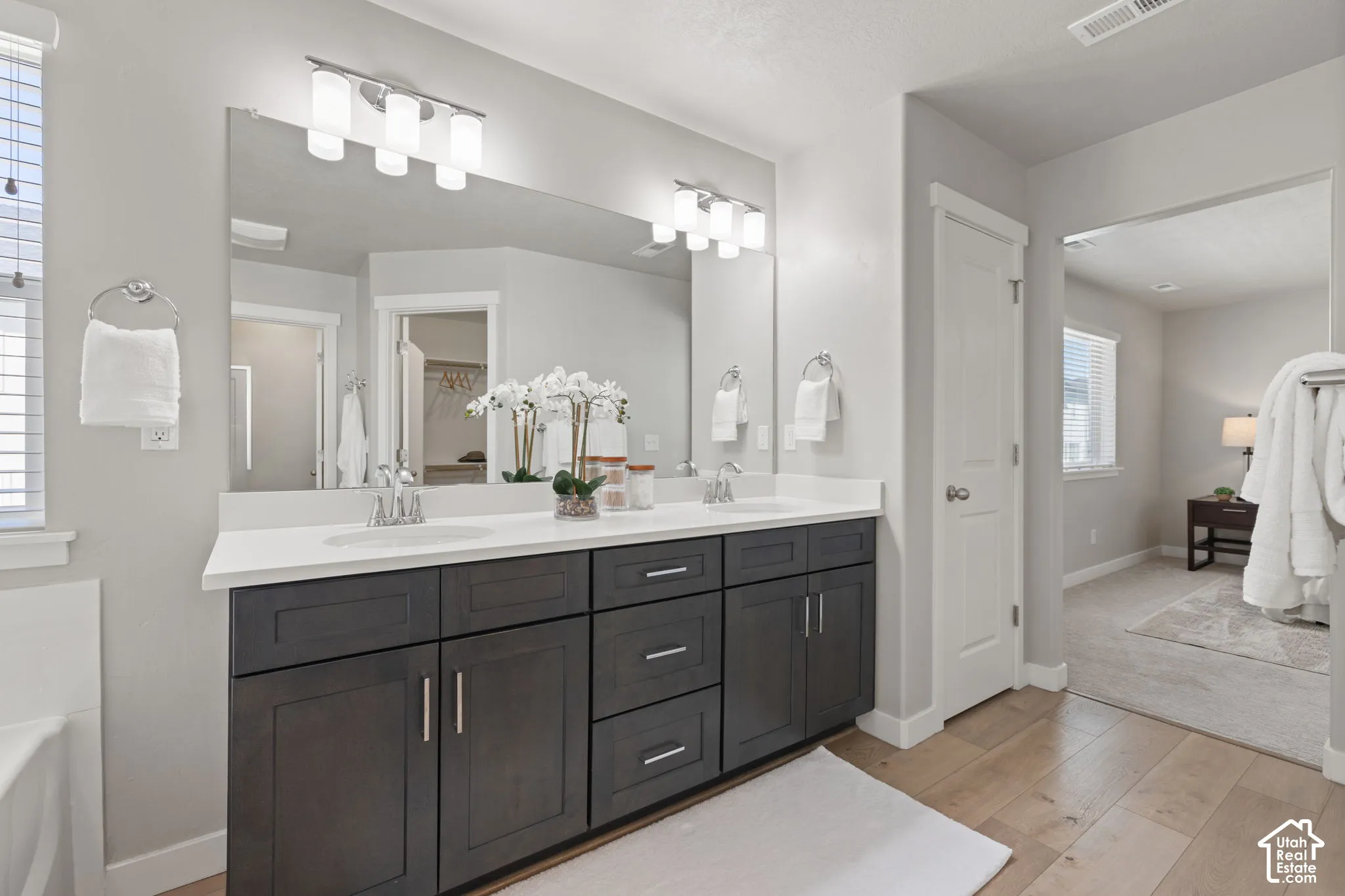 Dual vanity with dark wood-finish cabinetry, white countertops, and a large wall-mounted mirror