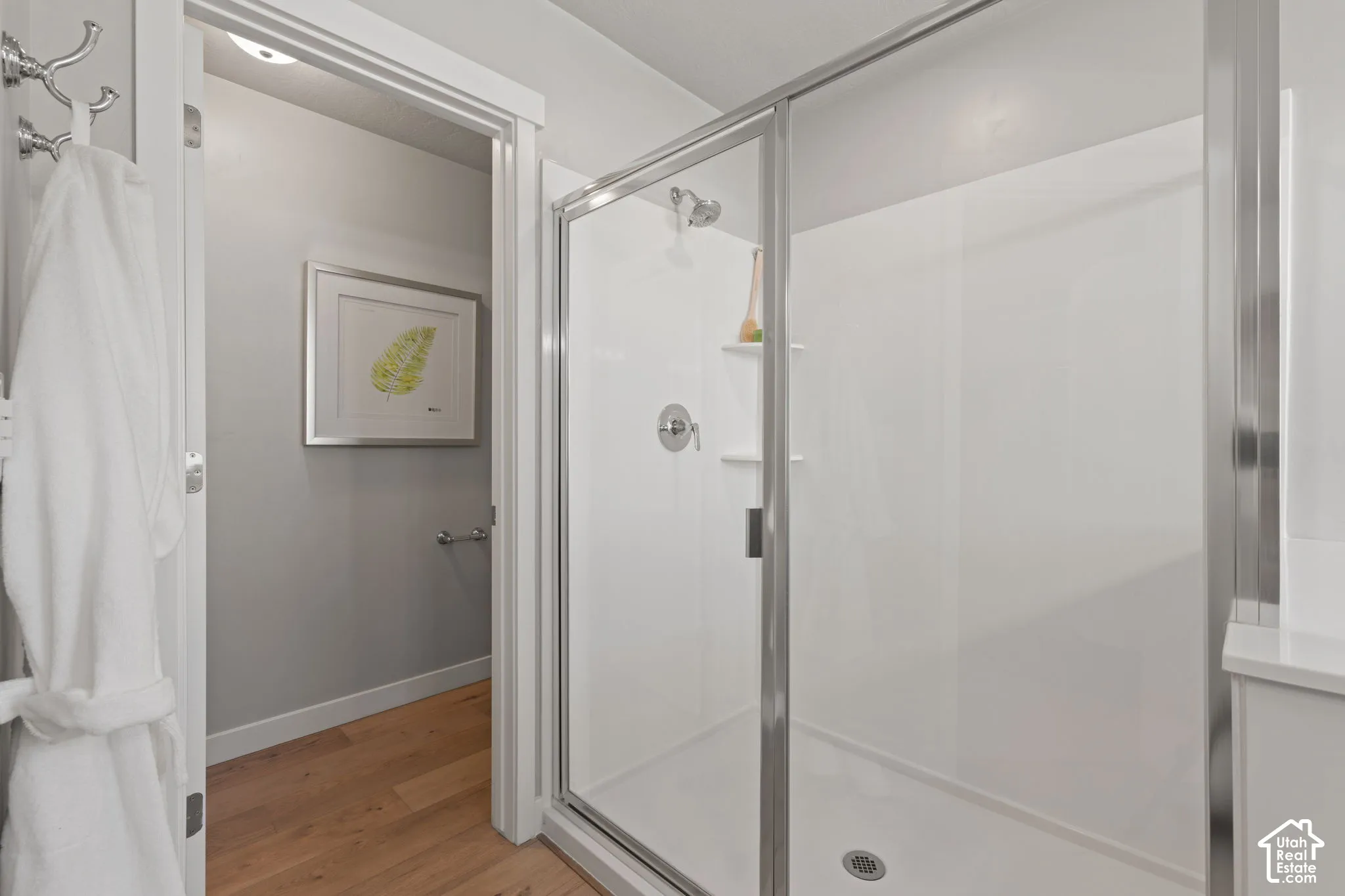 Enclosed shower with a glass door, chrome fixtures, and built-in shelving