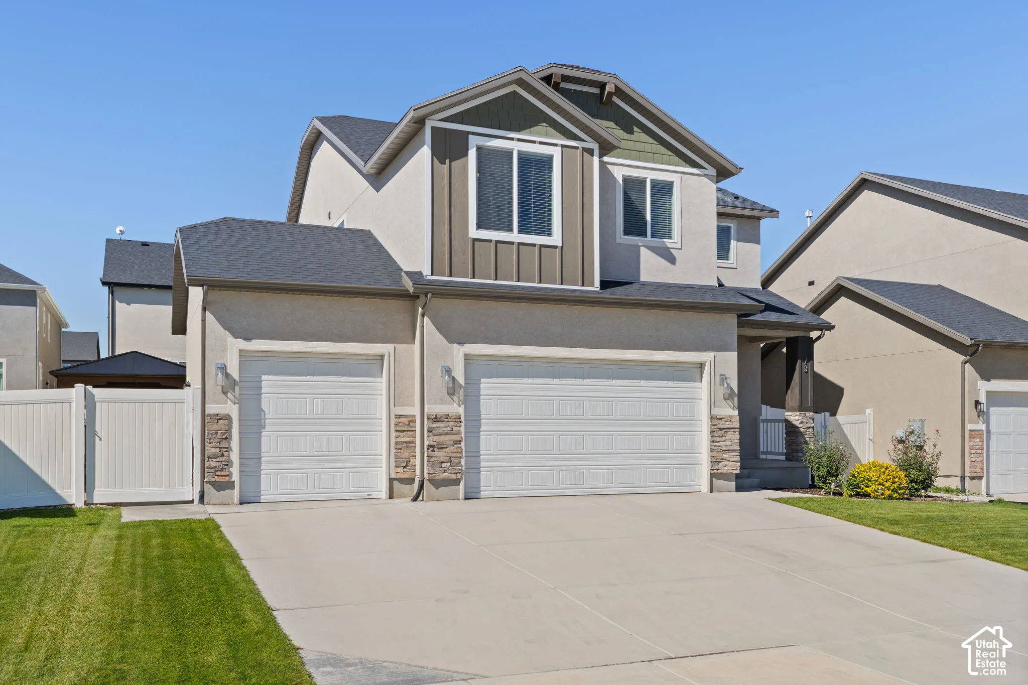 Contemporary exterior with stucco siding, stone accents, multiple garage doors, and a paved driveway