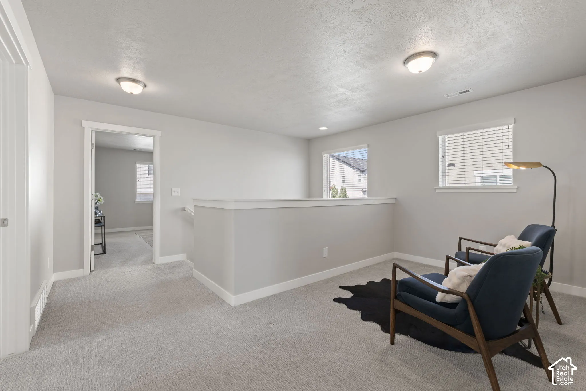 Carpeted landing with white trim, two windows with blinds, and flush-mount lighting