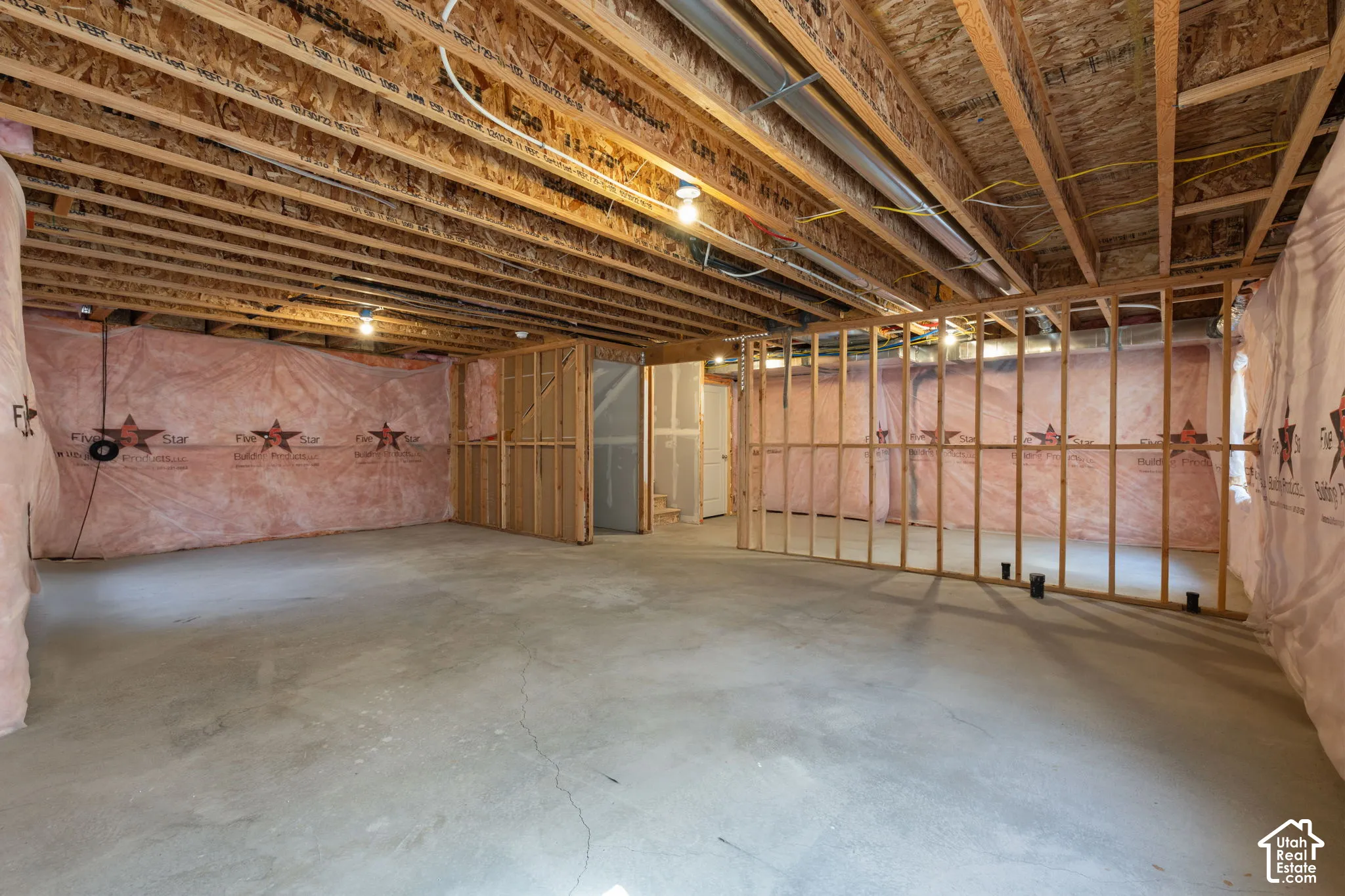 Unfinished basement featuring exposed wood joists, concrete flooring, and framed interior walls