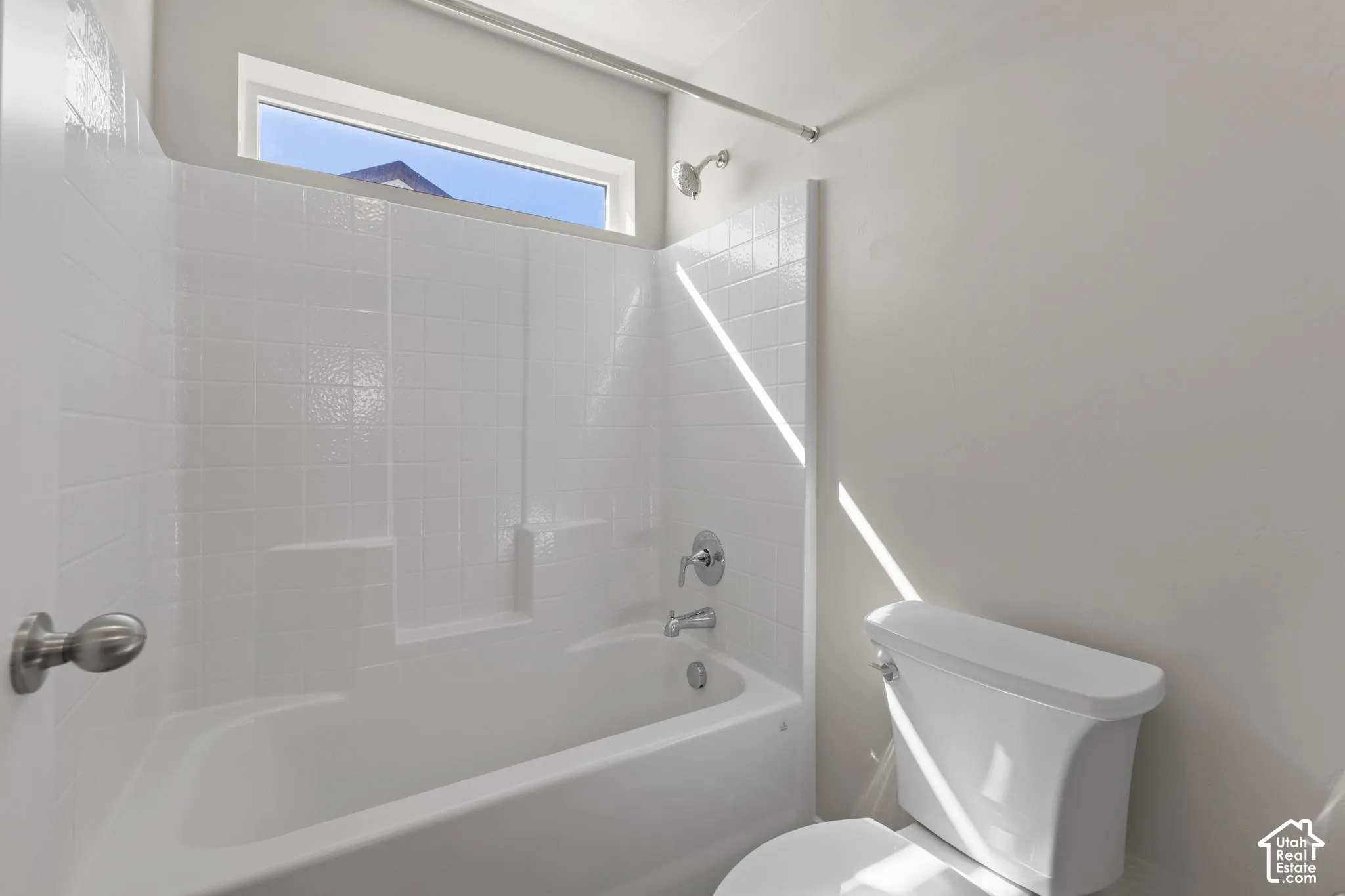 White tile-surround bathtub and shower with chrome fixtures