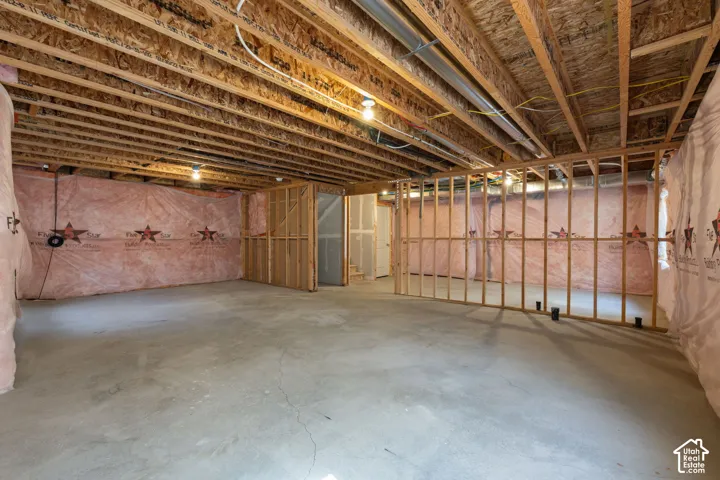 Unfinished basement featuring exposed wood joists, concrete flooring, and framed interior walls
