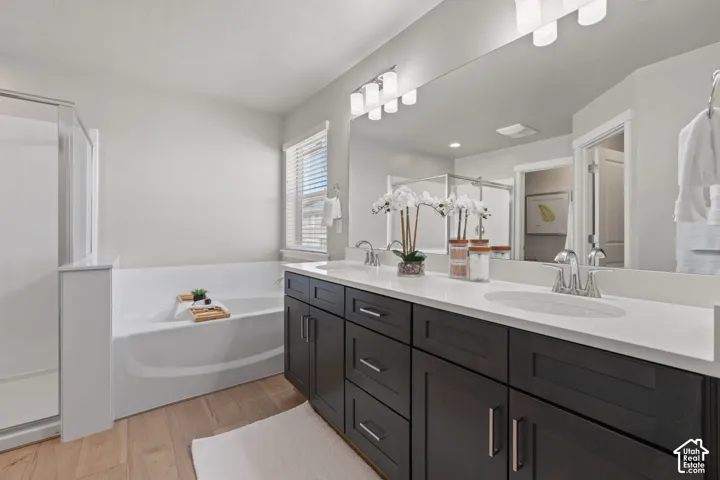 Dual sink vanity with dark wood-finish cabinetry, white countertops, built-in bathtub, and an adjacent glass-enclosed shower