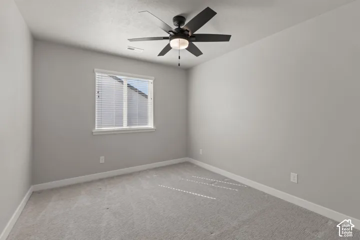 Neutral-toned carpeting, white window trim, and a ceiling fan with integrated lighting