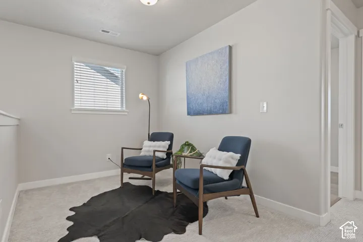 Neutral wall tones, carpeted flooring, and a single window with blinds