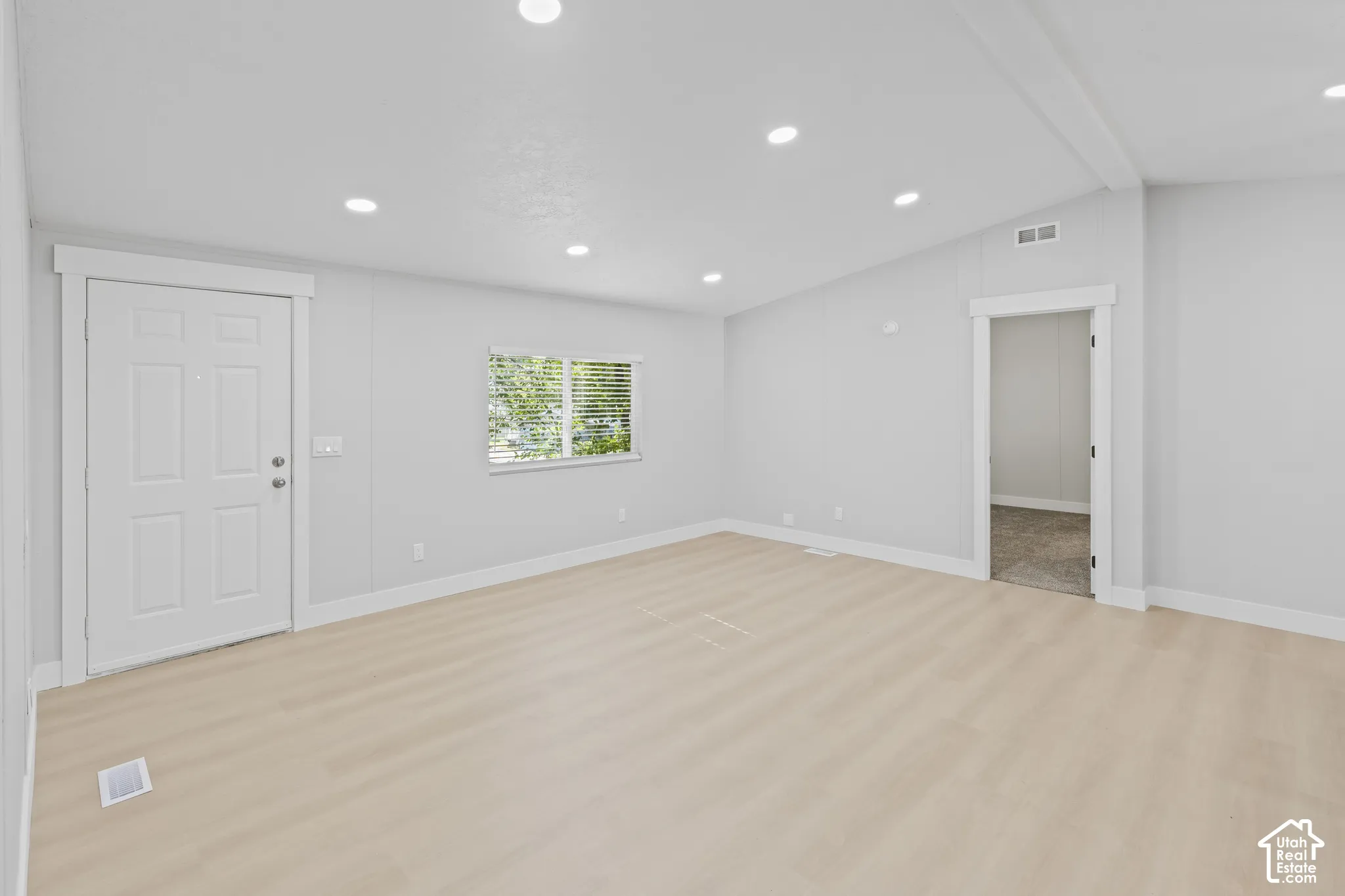 Recessed lighting, light wood-finish flooring, white trim, a multi-pane door, and a framed doorway