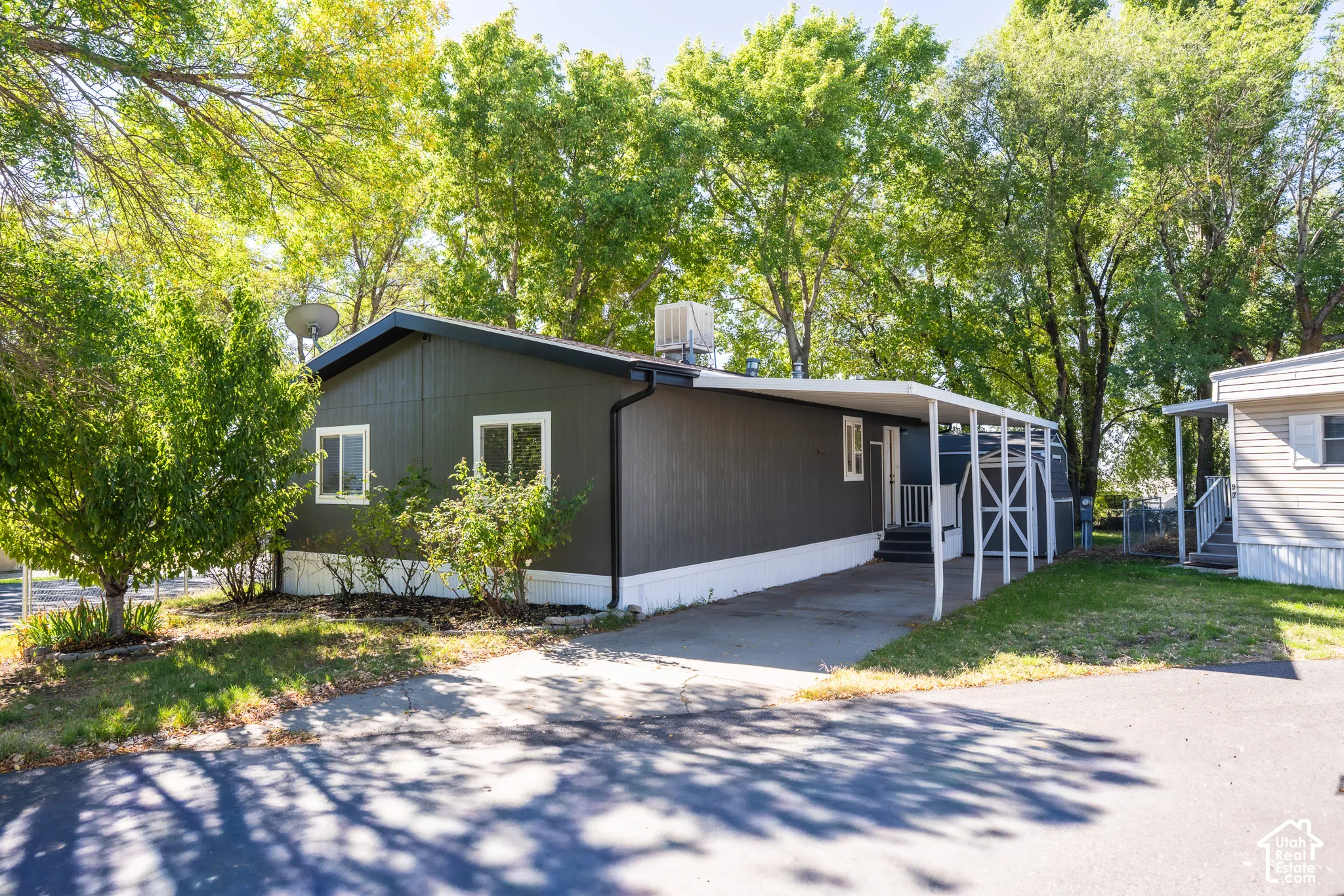 Dark-toned exterior siding with white trim windows and a covered carport entry