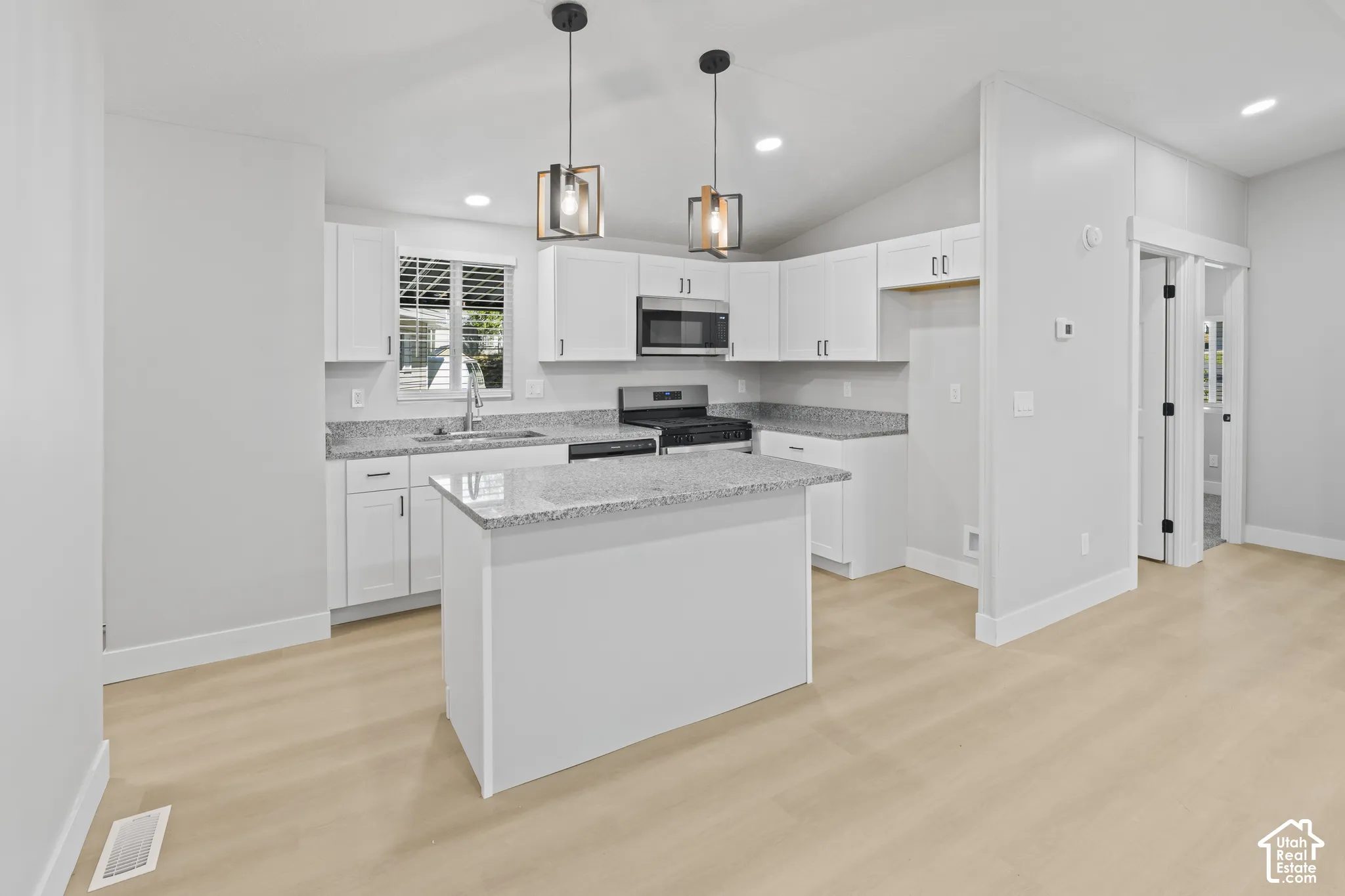 Kitchen featuring light wood-finish flooring, white cabinetry, a central island, and stainless steel appliances
