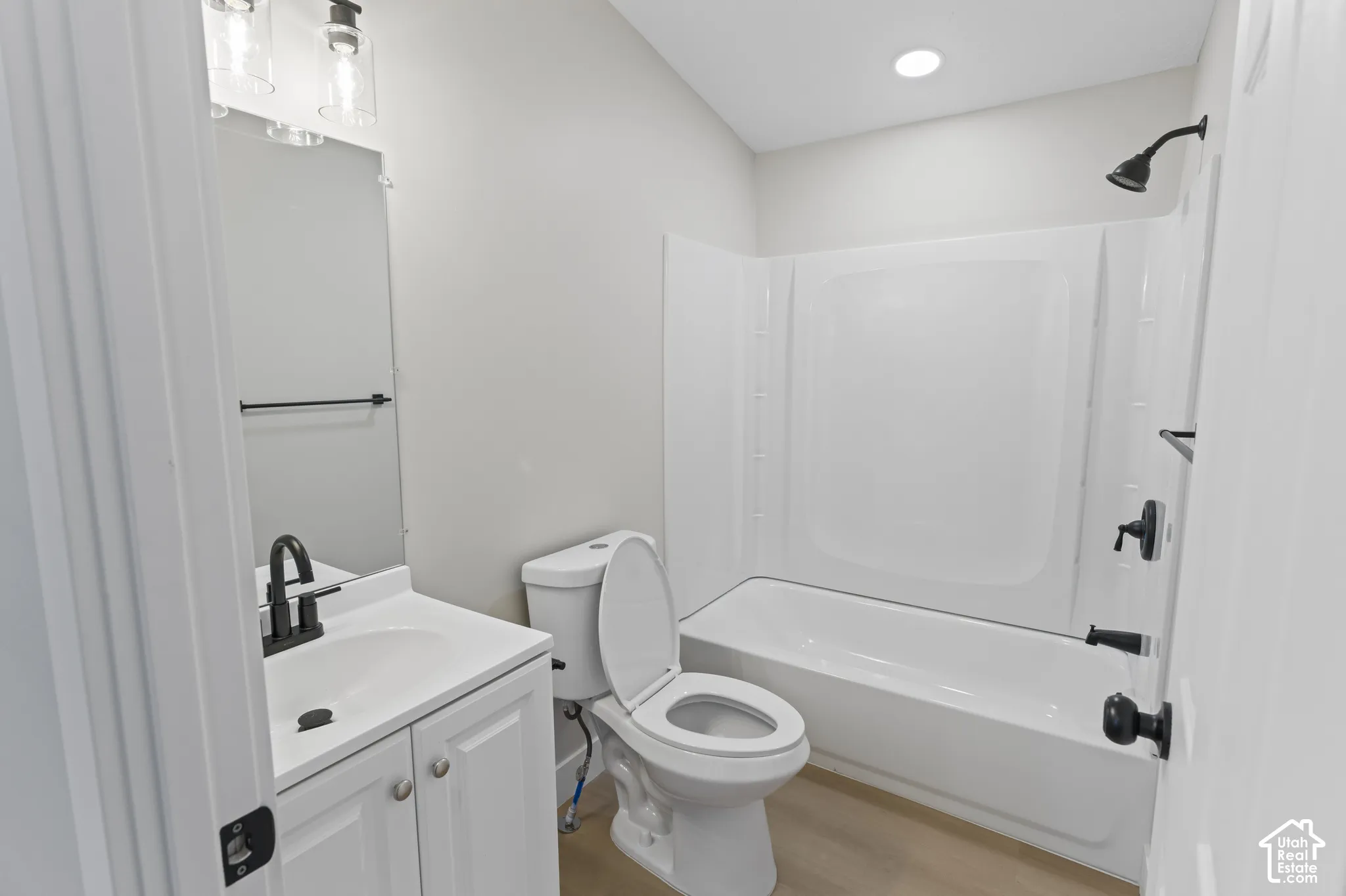 White vanity with a single basin sink, matte black faucet, and a two-light vanity fixture