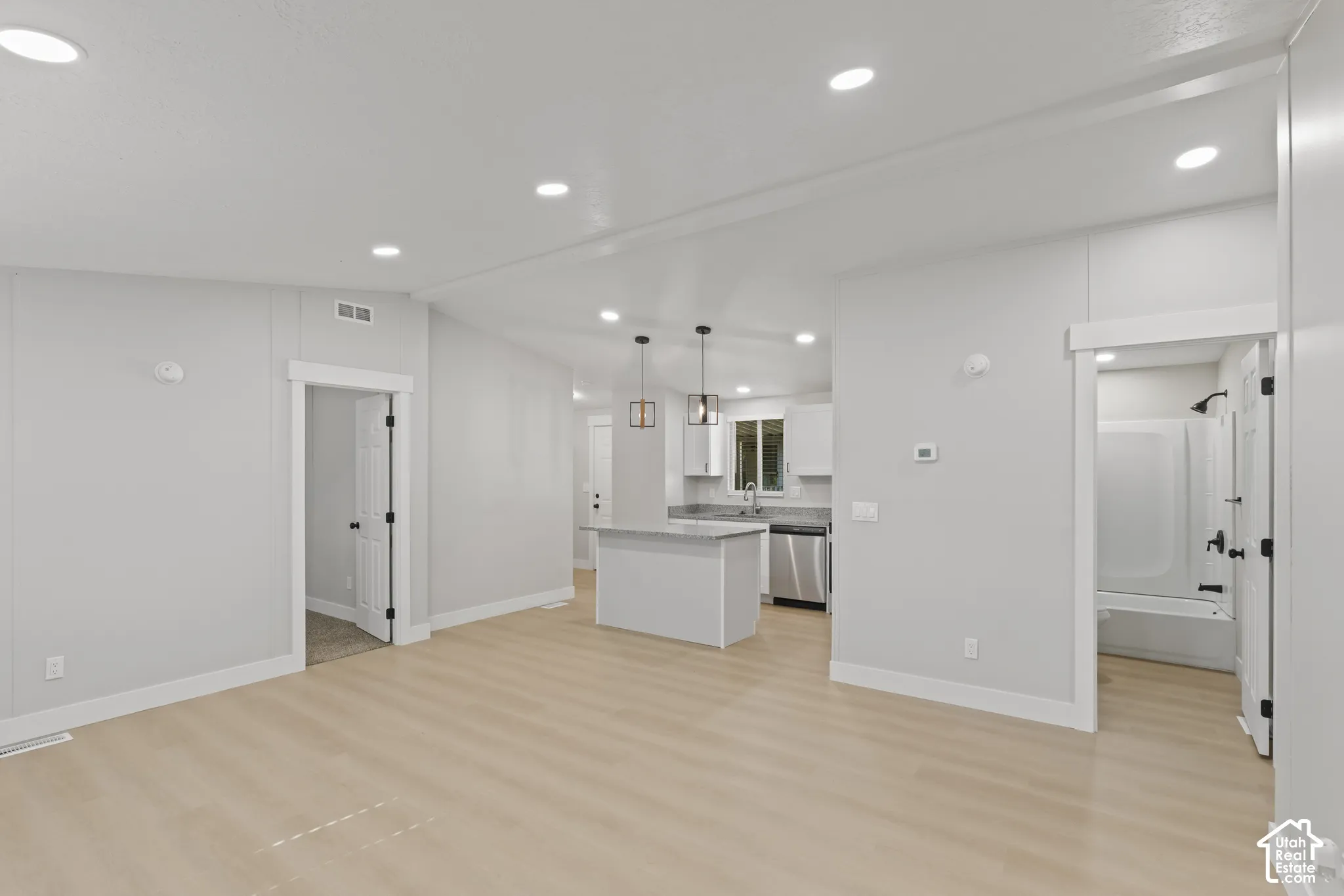 Open-concept living area featuring recessed ceiling lighting, wood-finish flooring throughout, and seamless sightlines to the kitchen