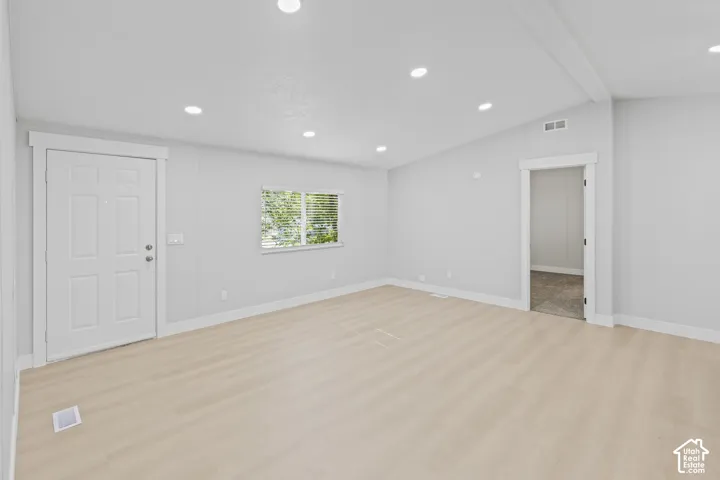 Recessed lighting, light wood-finish flooring, white trim, a multi-pane door, and a framed doorway