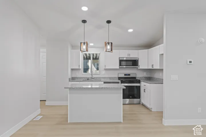 Kitchen featuring white cabinetry, stainless steel appliances, granite-style countertops, wood-finish flooring, and recessed lighting