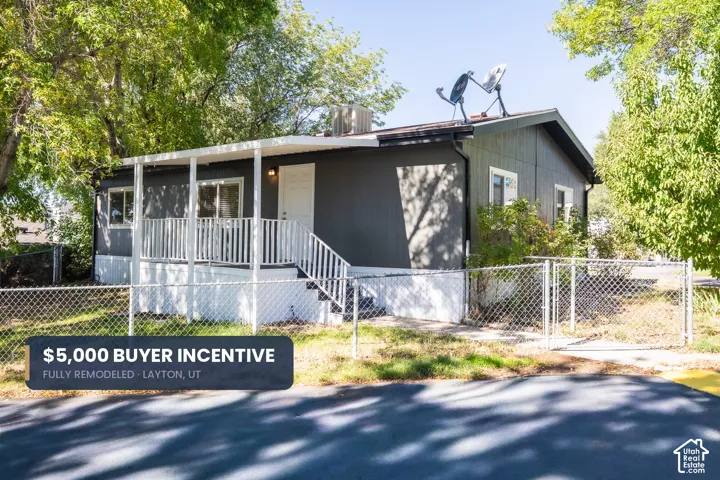 Front exterior with a covered porch, white railing, and dark siding