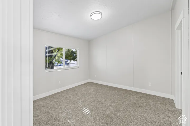 Carpeted room with a flush-mount ceiling light fixture, a window with blinds, and white trim