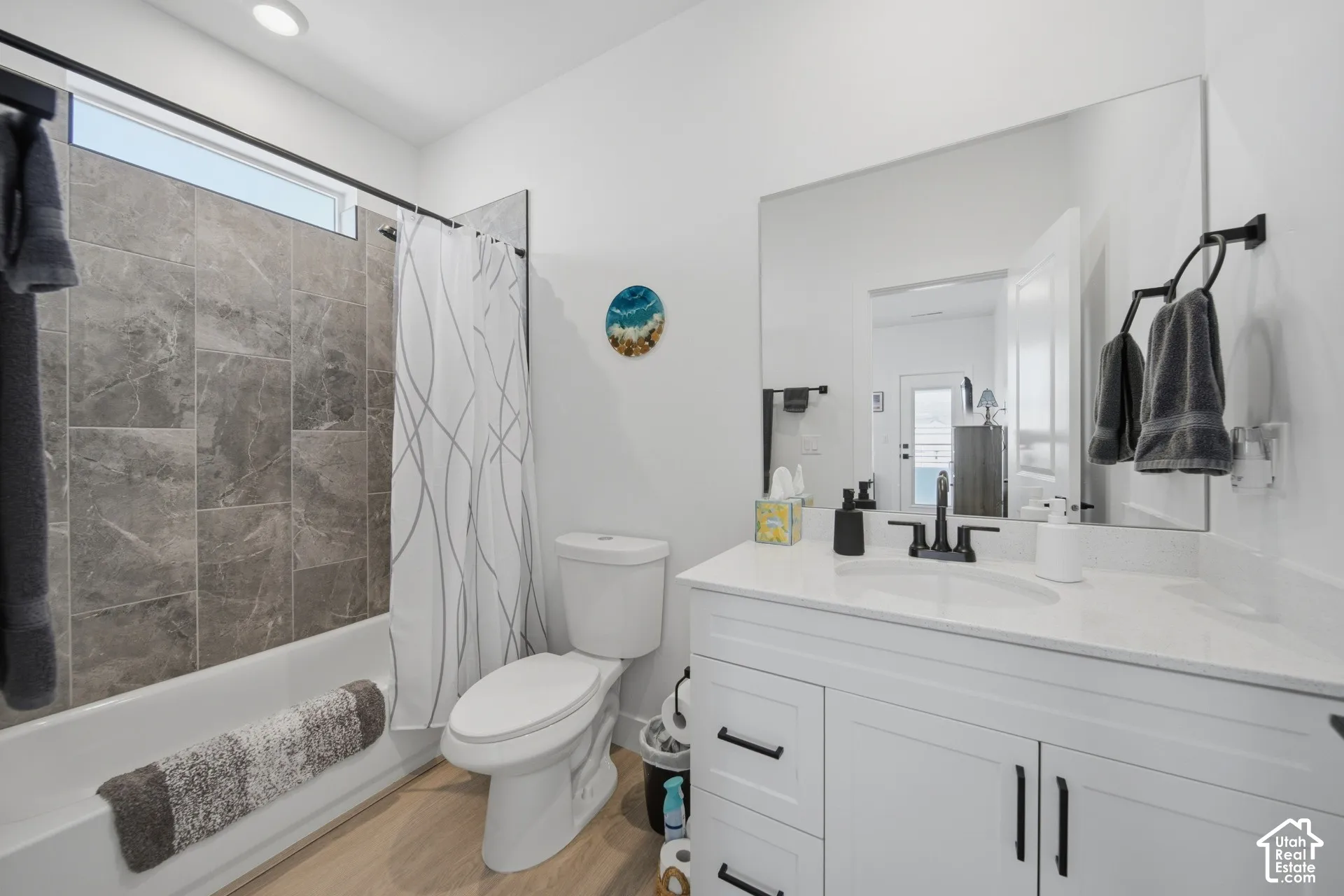 White vanity with black hardware, integrated sink, and a large wall-mounted mirror