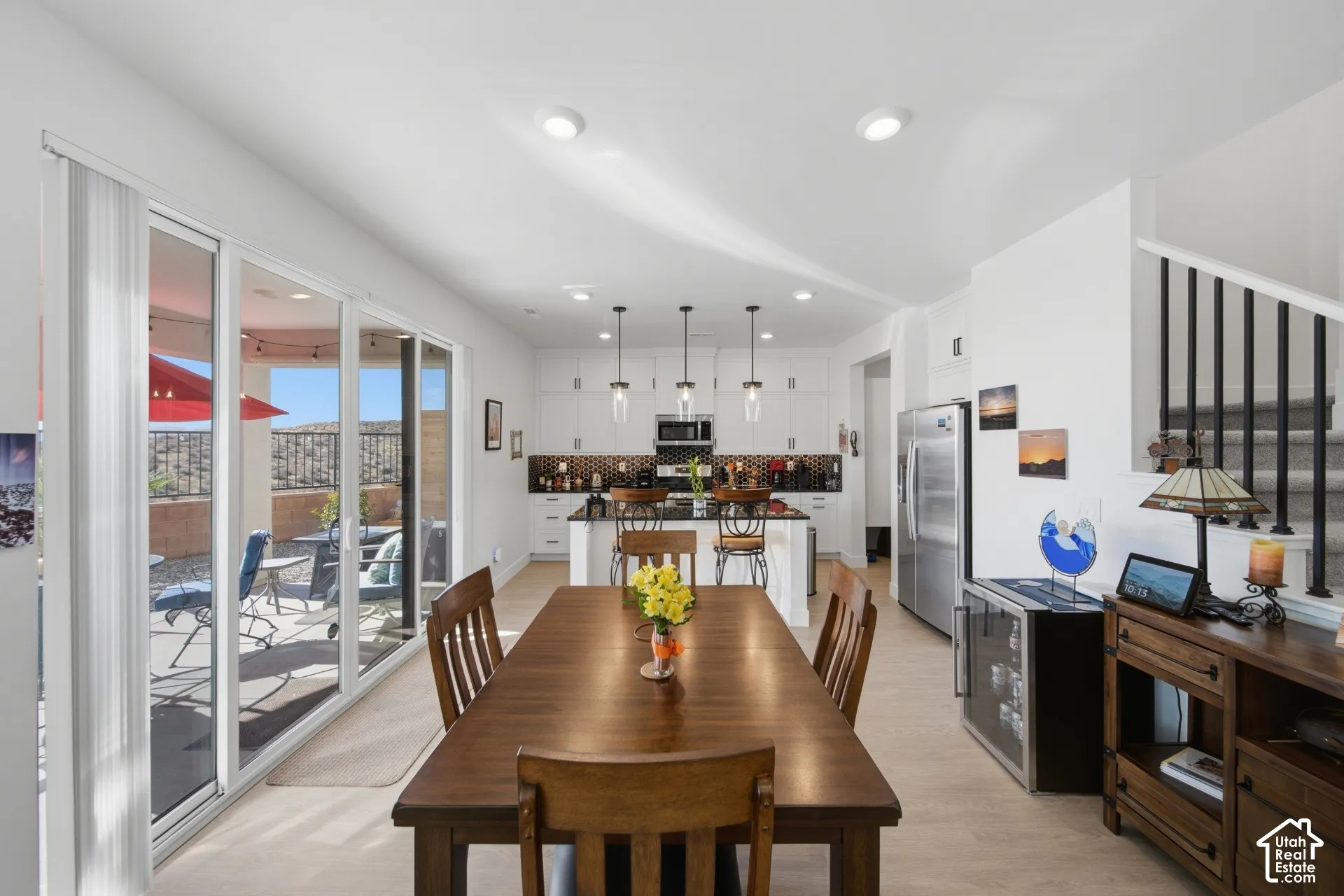 Spacious open-concept layout with light wood-finish flooring, recessed lighting, and large sliding glass doors leading to an outdoor patio