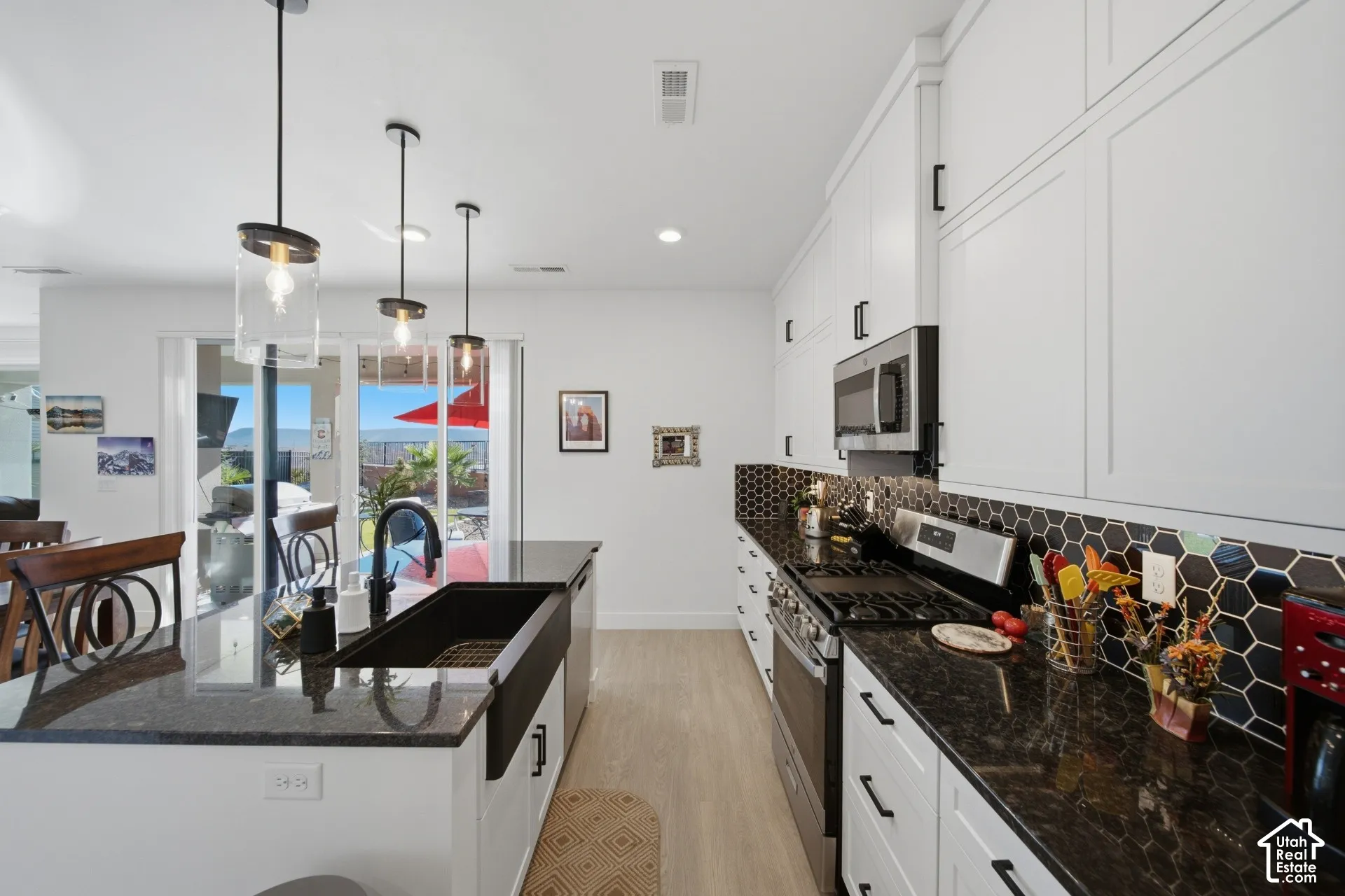 White cabinetry with black hardware, dark countertops, and a black hexagonal tile backsplash