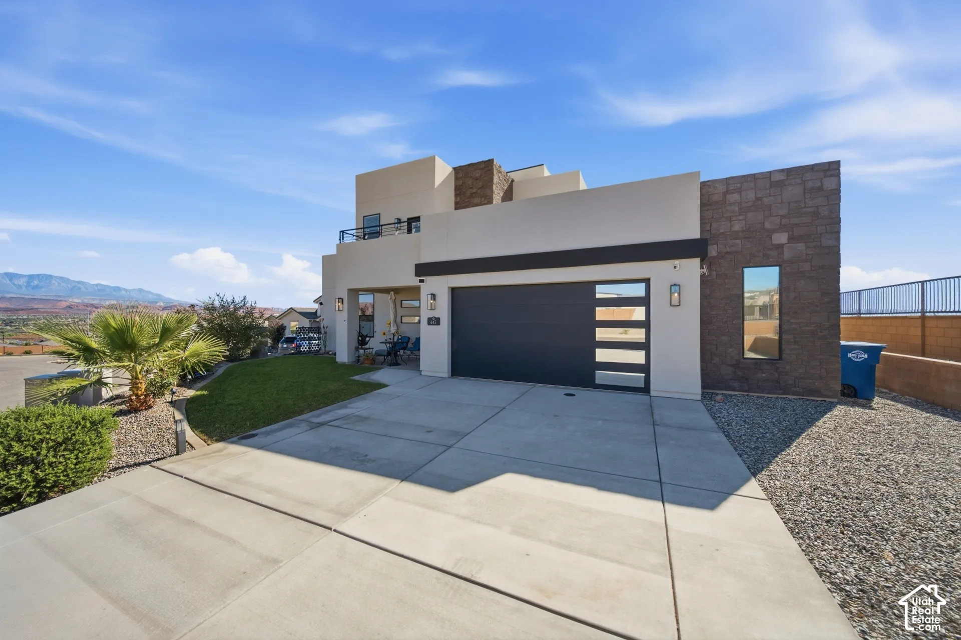 Contemporary exterior with stucco and stone accents, a modern garage door with frosted panels, and a concrete driveway