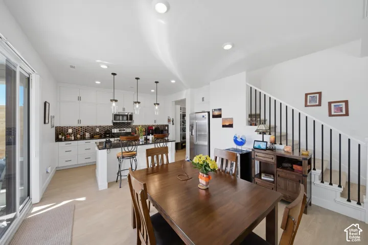 Bright open-concept kitchen with white cabinetry, stainless steel appliances, and a dark patterned backsplash