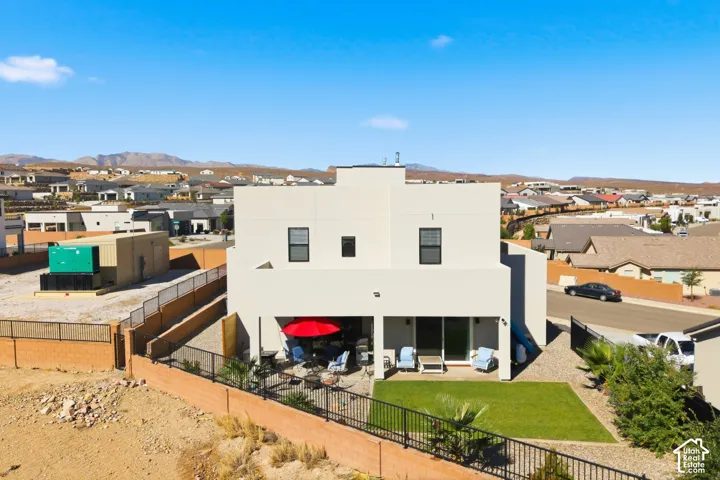 Modern-style exterior with a stucco finish, ground-level patio, and a landscaped yard featuring a lawn and gravel